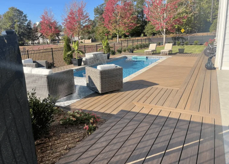 Custom composite deck around pool with lounge furniture and fall foliage — JHG Contracting LLC serving Decatur, AR